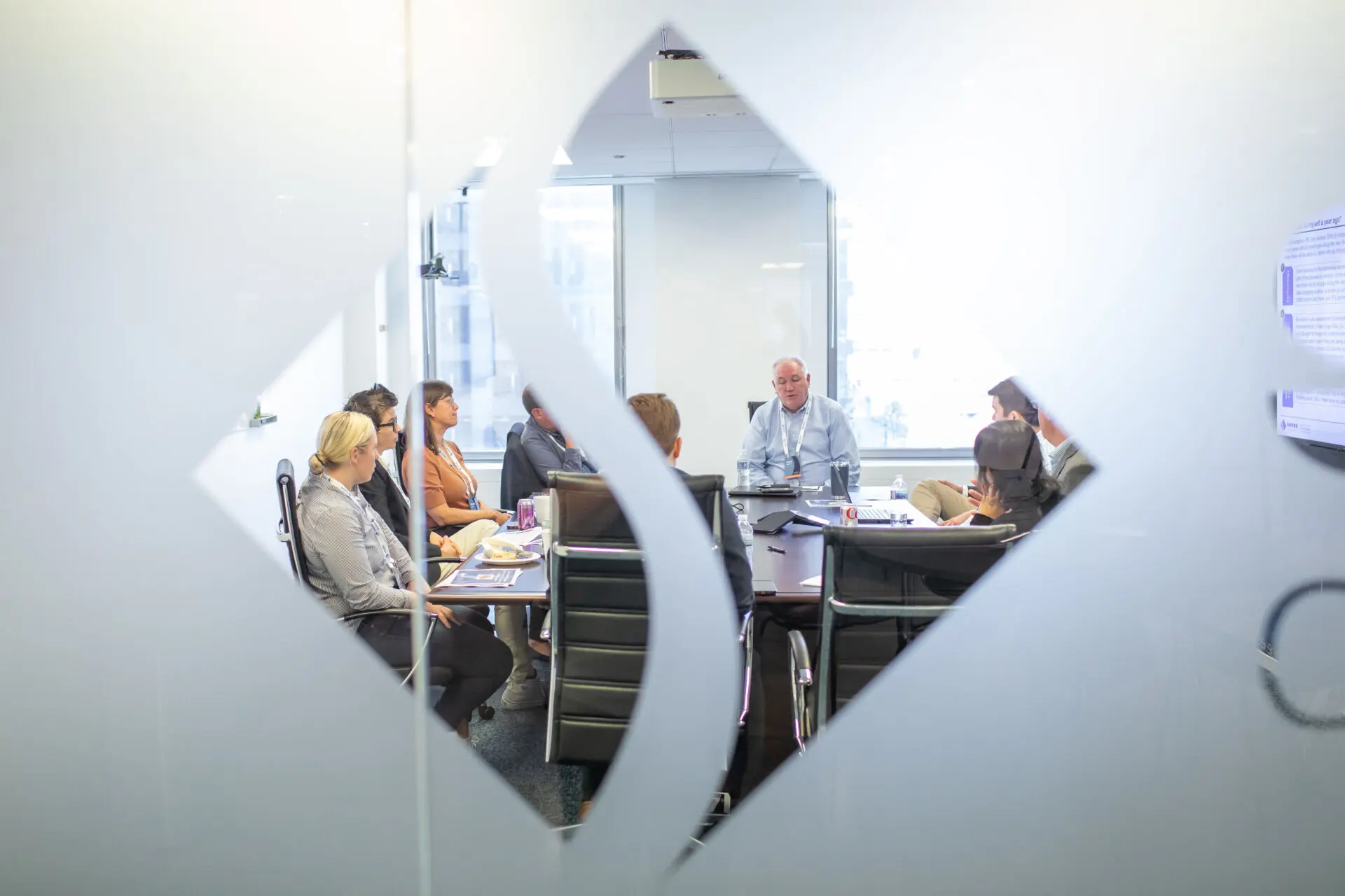 Conference Room Meeting visible through frame of Shore Capital Partners Logo on frosted glass doors