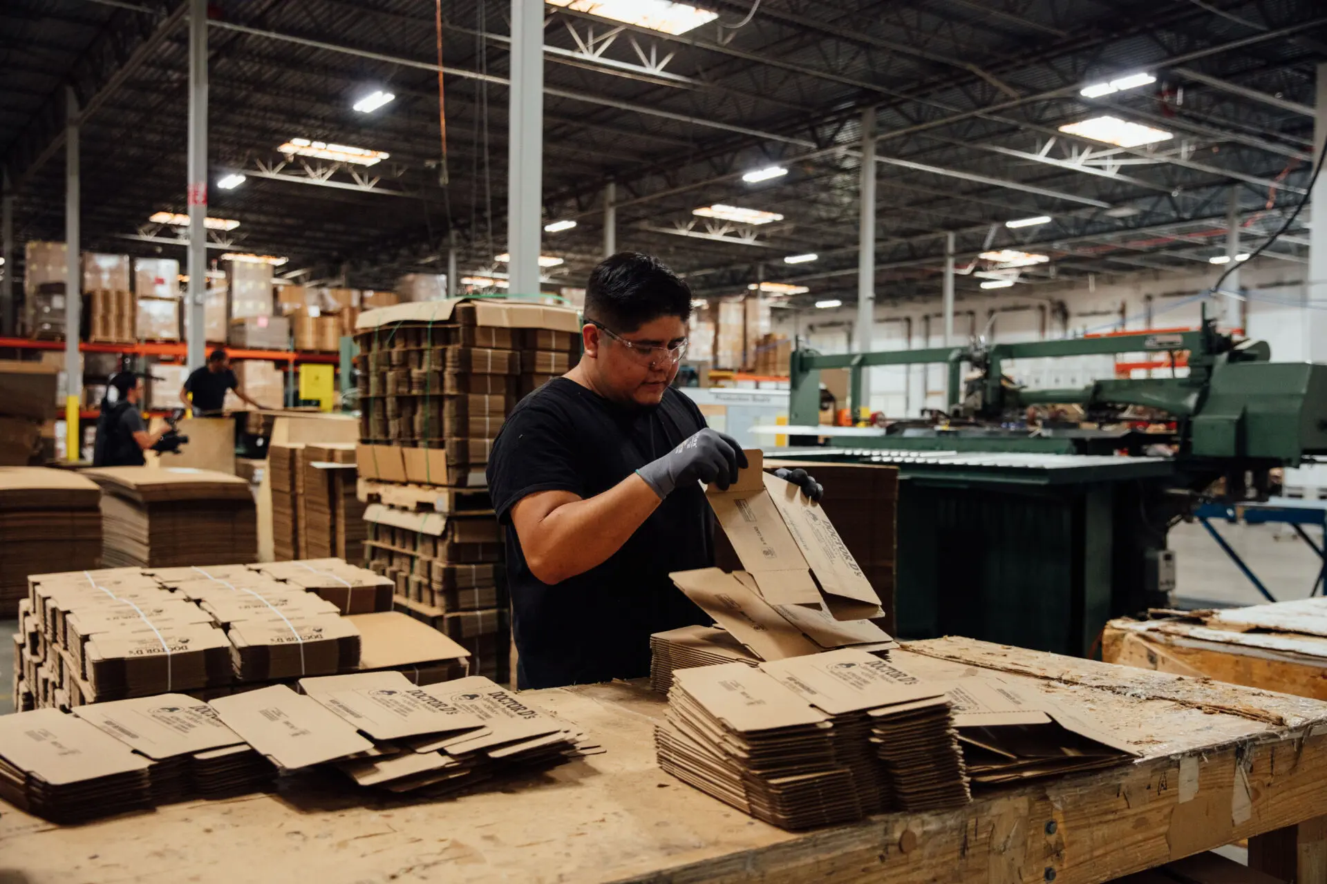 Worker assembles cardboard packaging in industrial packing facility