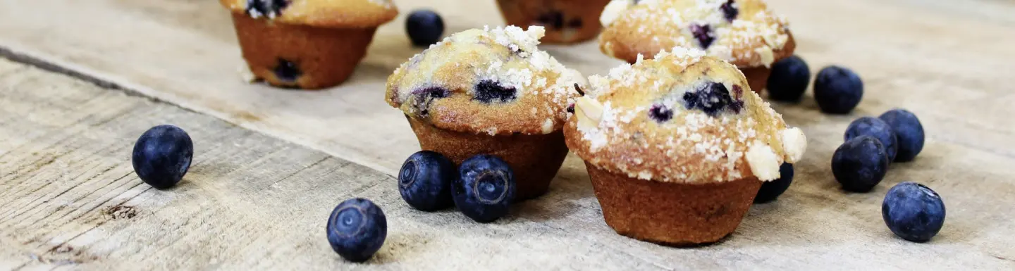 blueberry mini muffins and fresh blueberries on rustic wood countertop